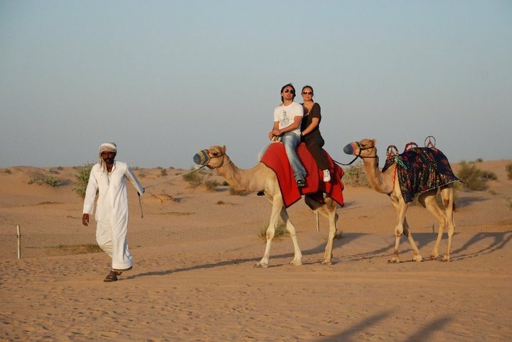 una coppia in cammello guidati da un beduino nel deserto
