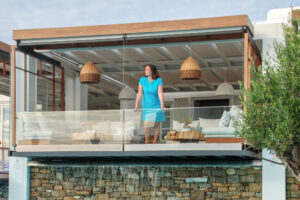 donna con abito turchese, affacciata al terrazzo di un hotel di lusso.