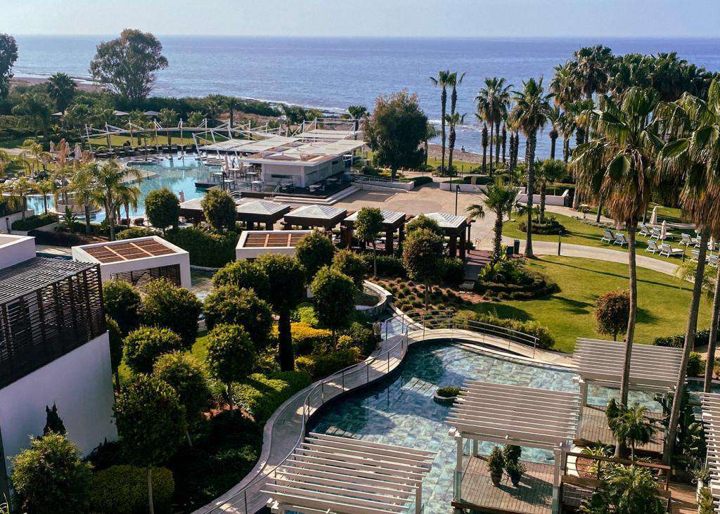 vista del parco di un resort con giardino, palme, mare e piscine