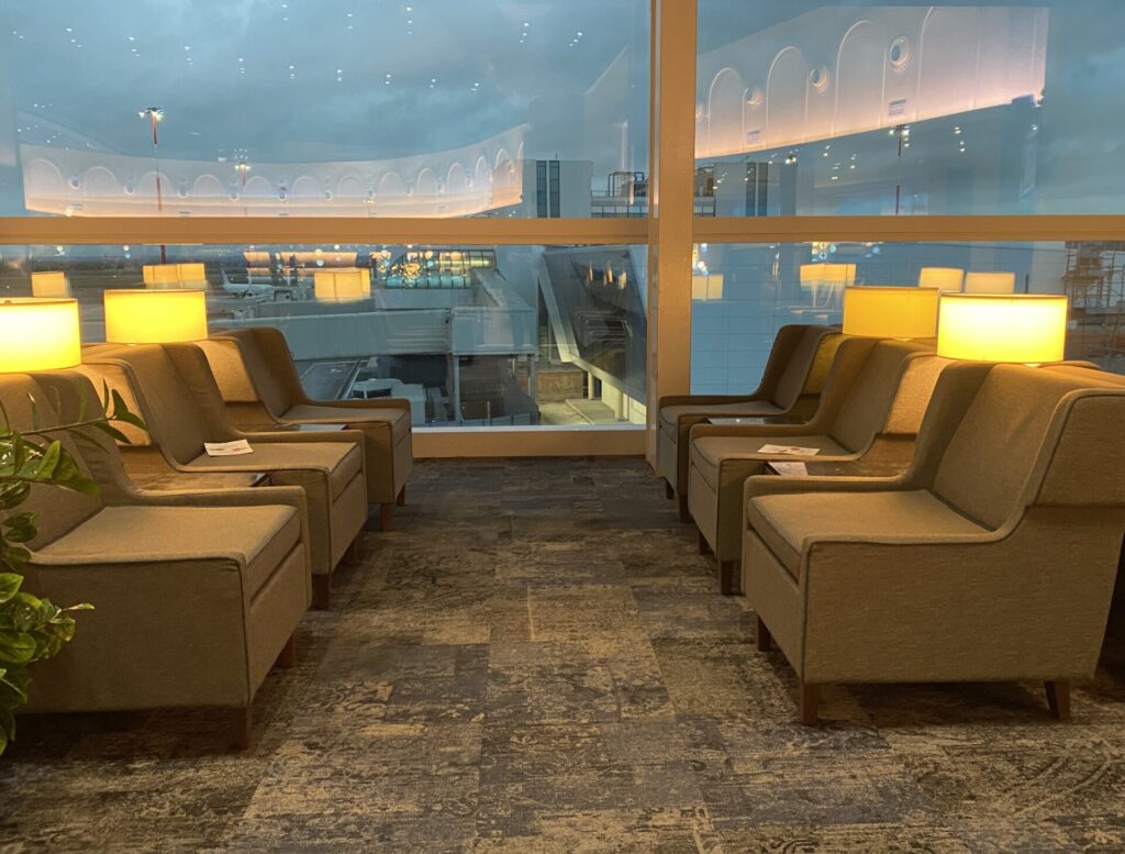 salottini illuminati da luci da tavolo con vetrate e vista sulle piste dell'aeroporto